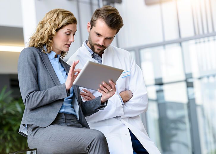 Businesswoman with tablet and doctor talking in hospital