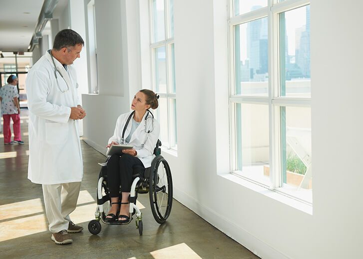 Caucasian paraplegic doctor and colleague talking in hospital