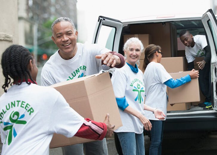 Volunteers passing cardboard boxes from delivery van