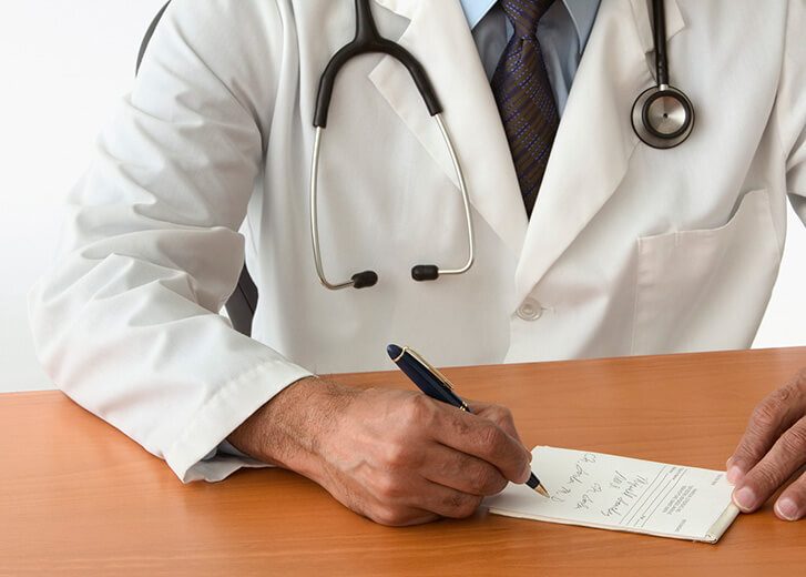 Mid section view of a male doctor writing a prescription