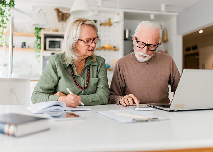 Senior couple using laptop while planning their home budget, Happy senior couple going through home finances and using computer at home.