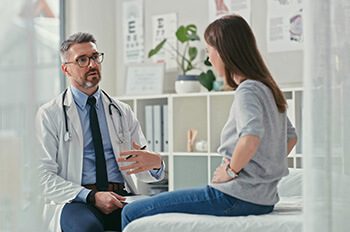 Shot of a mature doctor sitting with his patient in the clinic and asking questions during a consultation