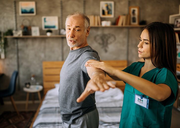 Senior adult, male patient does arm exercises with home healthcare nurse or physical therapist in nursing home or home setting