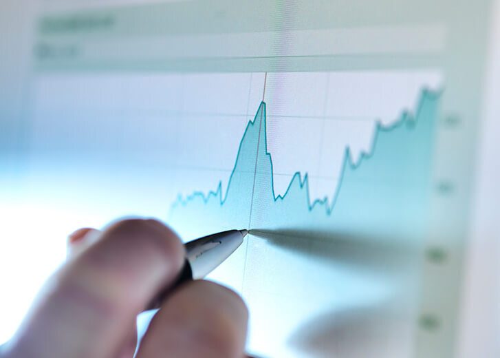 Hand of a stock broker analysing line graph on computer screen