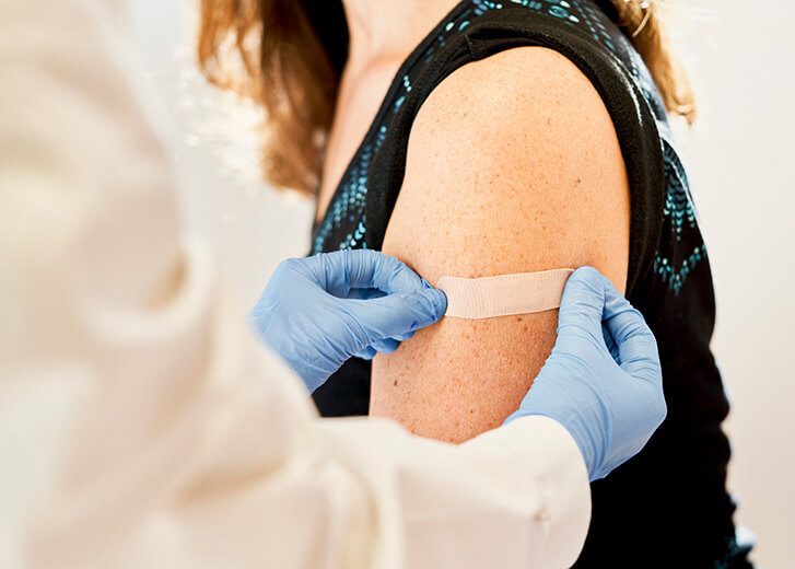 Doctor applying band-aid to his patients after receiving the third dose of vaccine for immunization