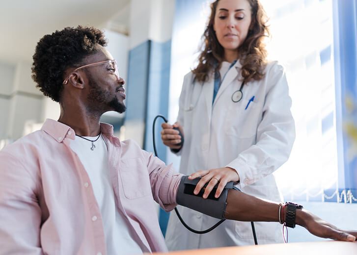 the man is attended to by a doctor who is checking his blood pressure.